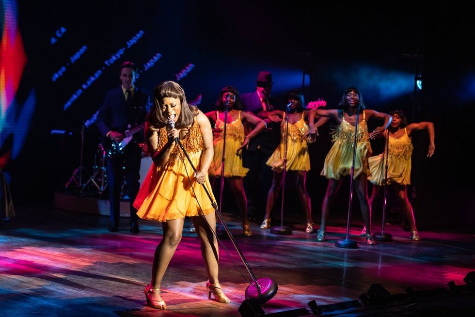Ari Groover at Tina Turner with the Ikettes behind her performing on stage.