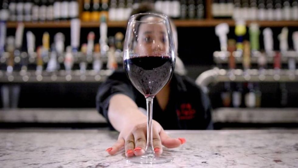 Bartender serving glass of wine