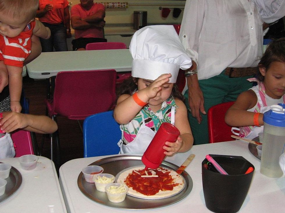 Child makes personal-sized pizza at Bake and Play Cafe in Dallas