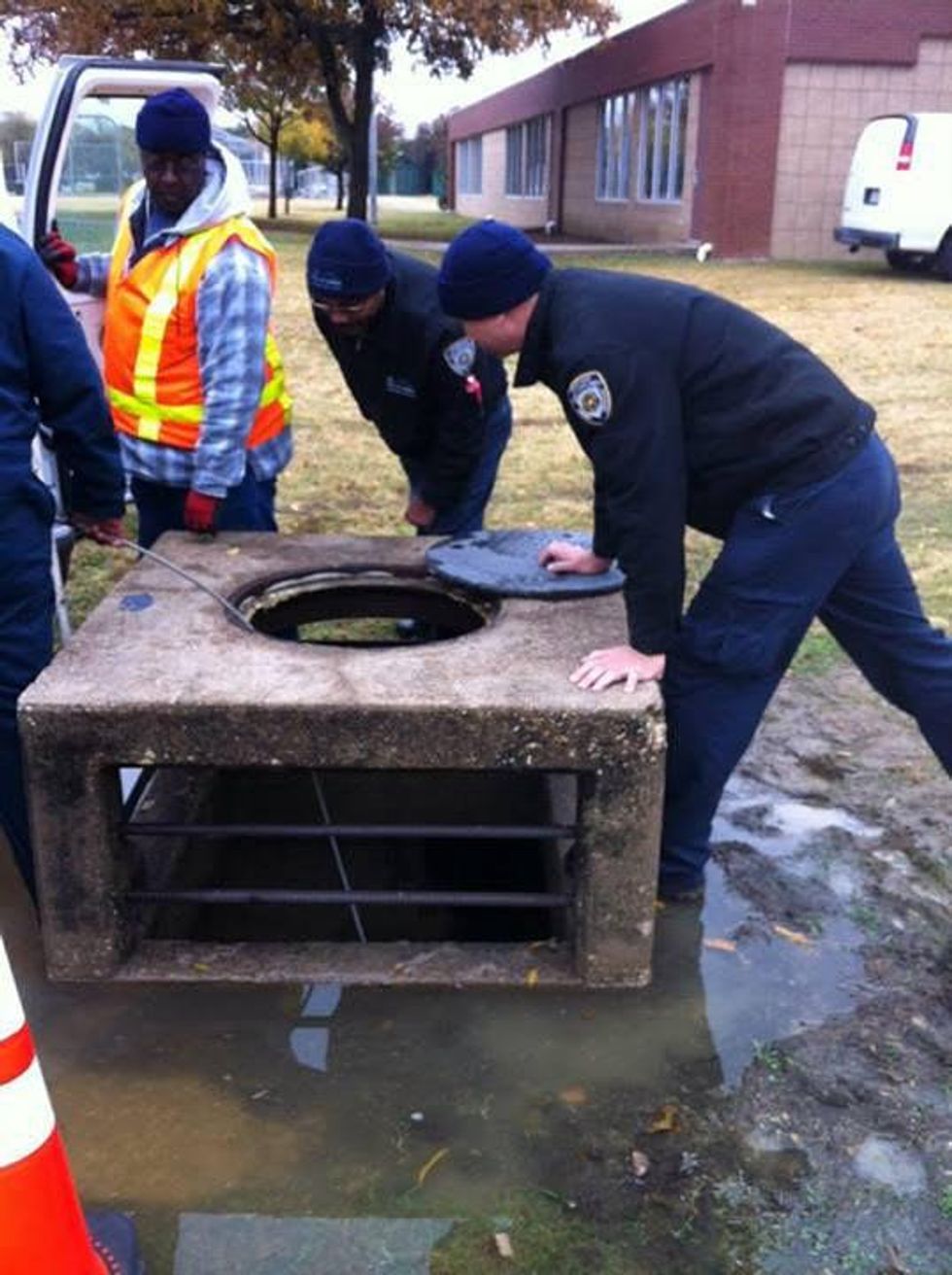 DAS employees at storm drain rescuing puppy