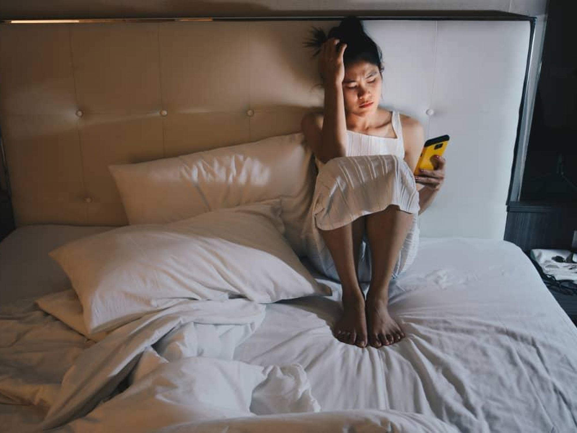 Depressed woman in bed looking at her phone