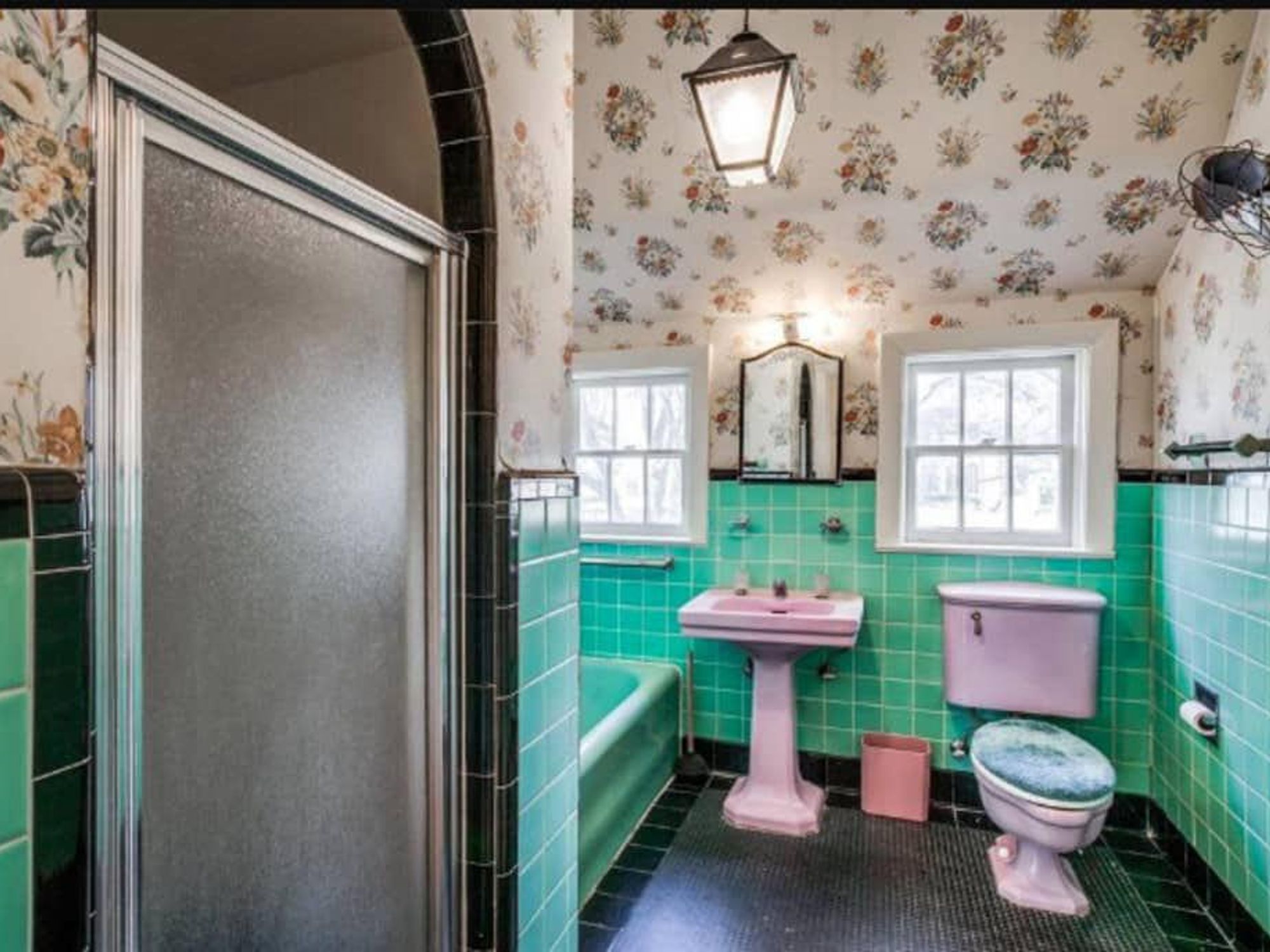 Green tile bathroom with glossy black trim comes with pink pedestal sink and commode.