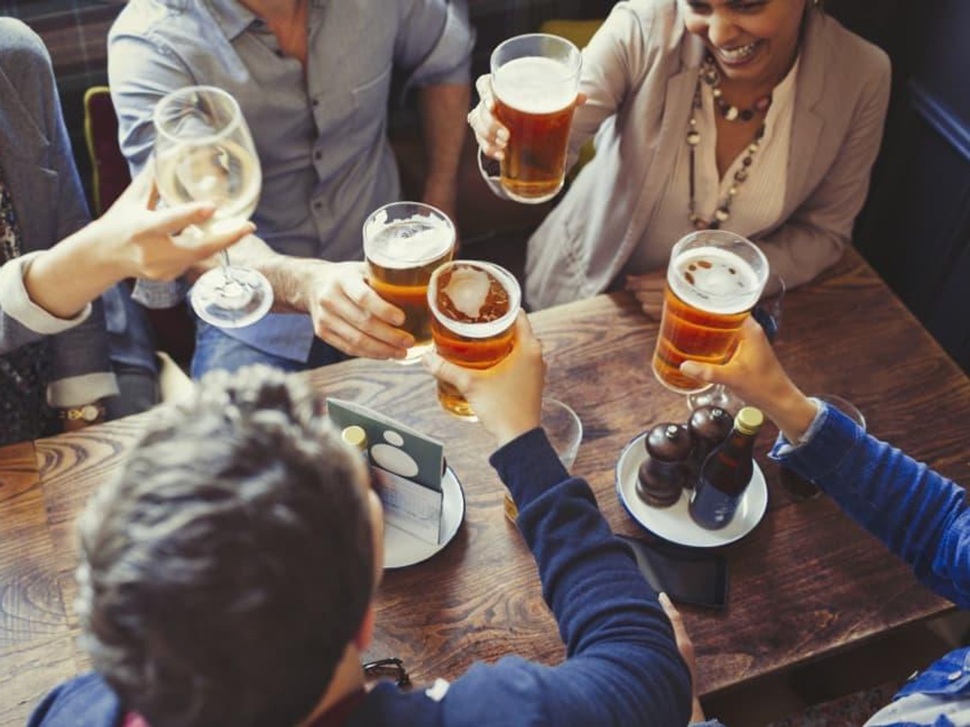 Group of people drinking beer at a bar cheers