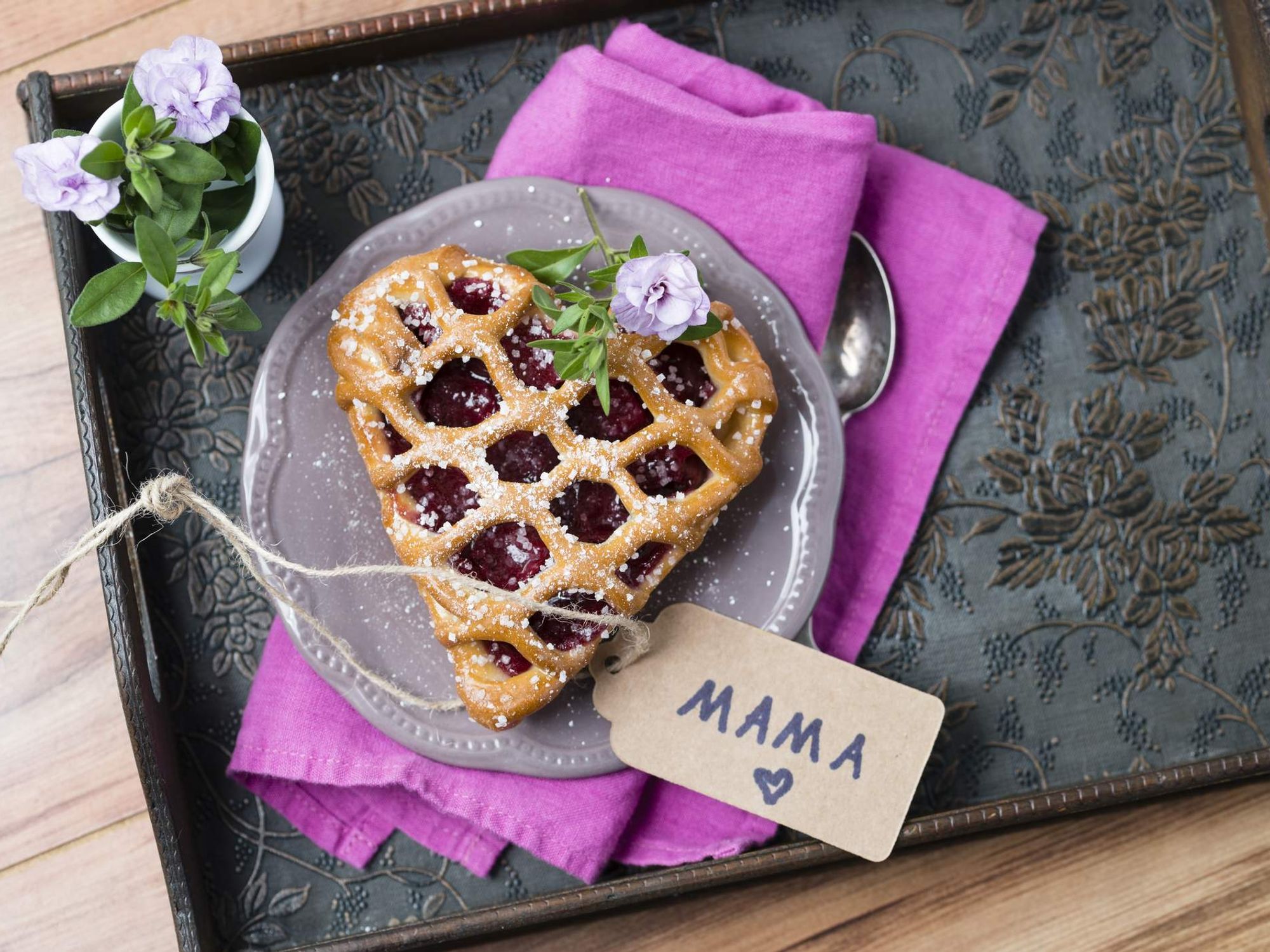 Heart-shaped cherry cake with name tag and flowers on tray