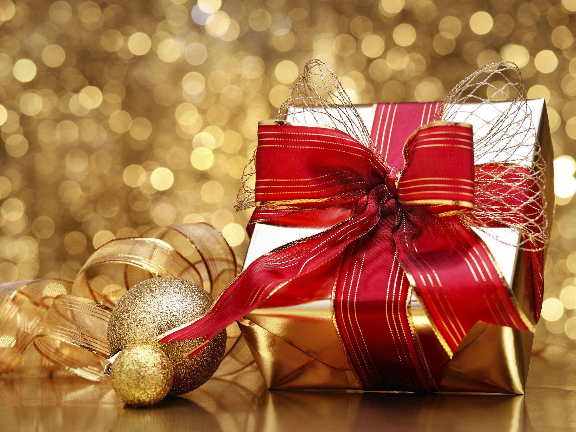Holiday gift wrapped in gold with red bow