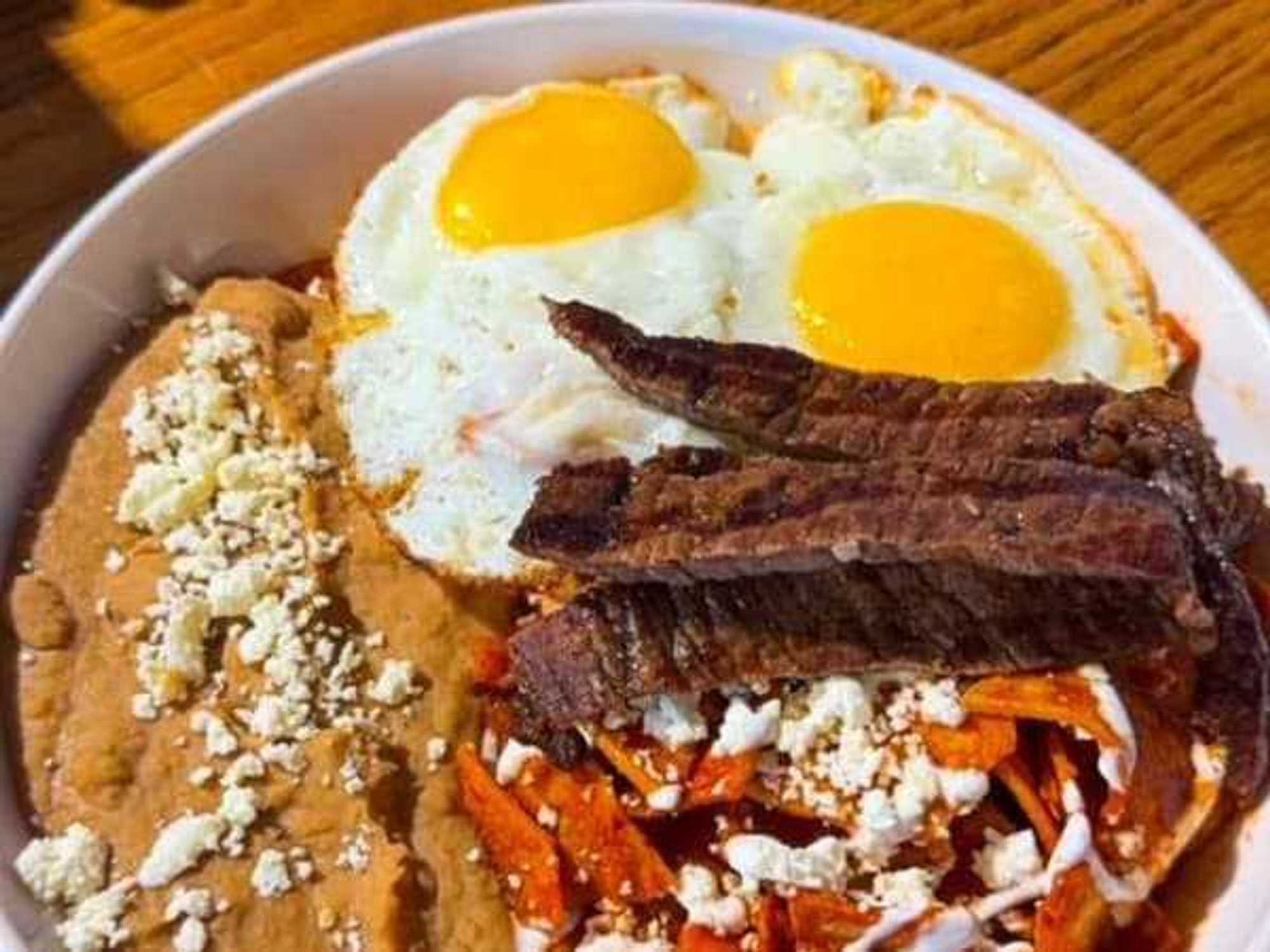 J’s Cafe's signature chilaquiles, topped with fried eggs, fajita steak, crema, cotija cheese.