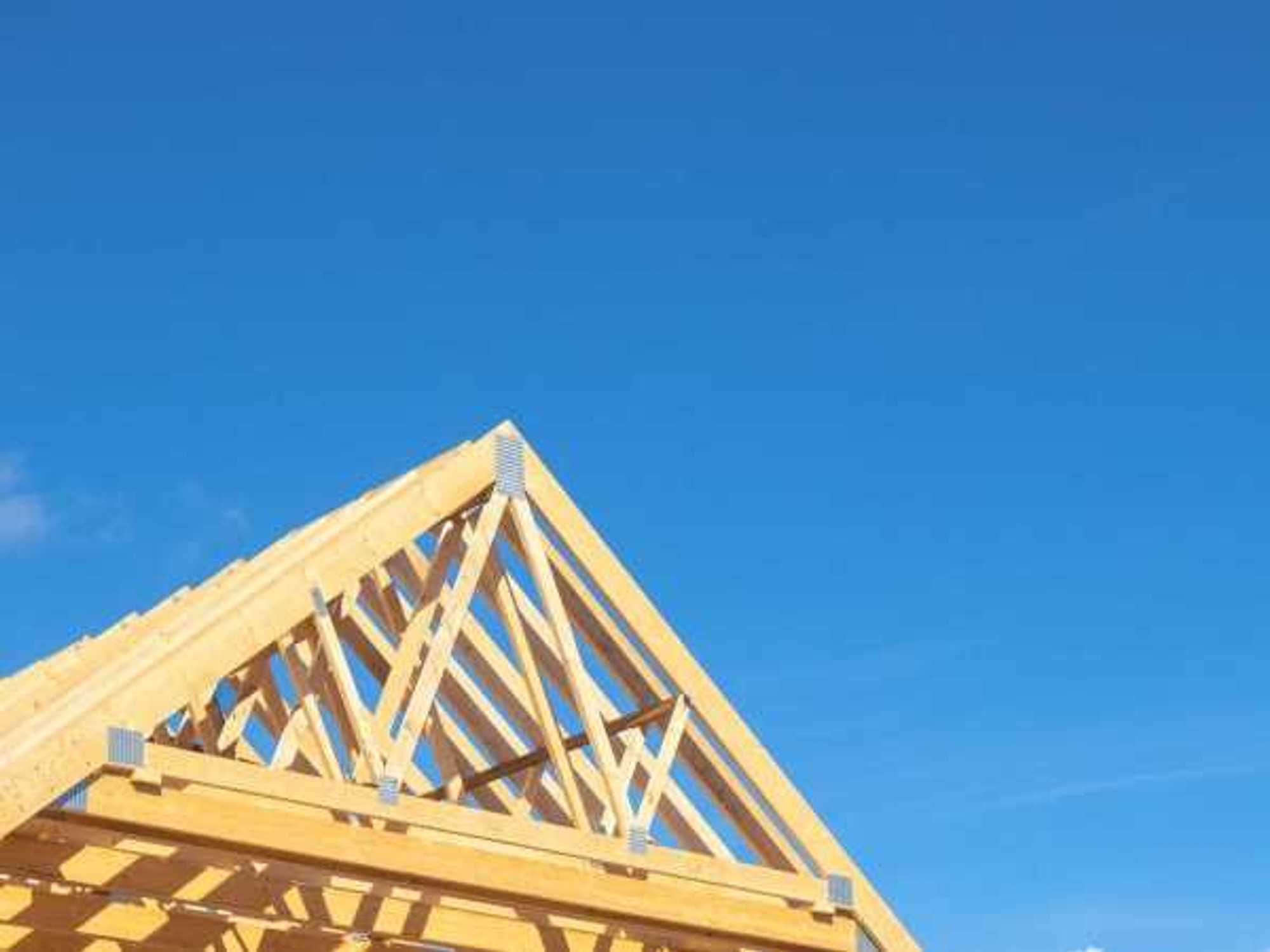 New residential construction home framing against a blue sky