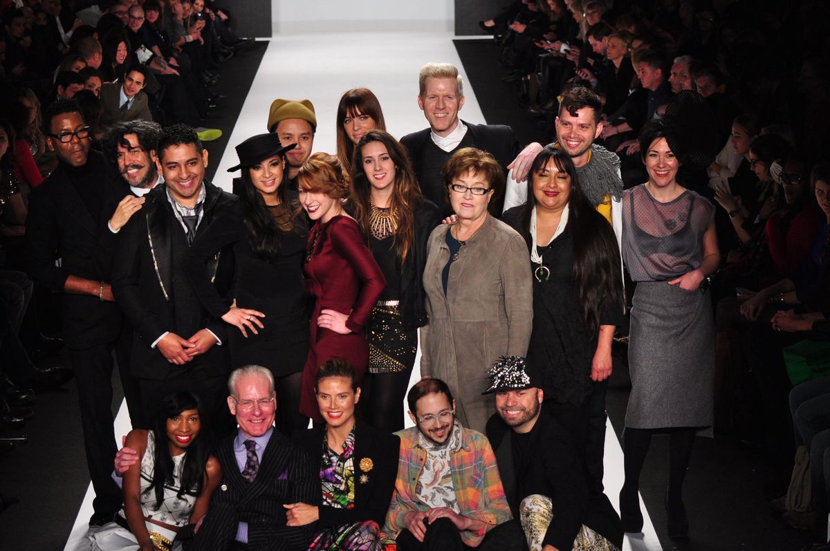 Project Runway cast pose on the runway with Tim Gunn, seated second