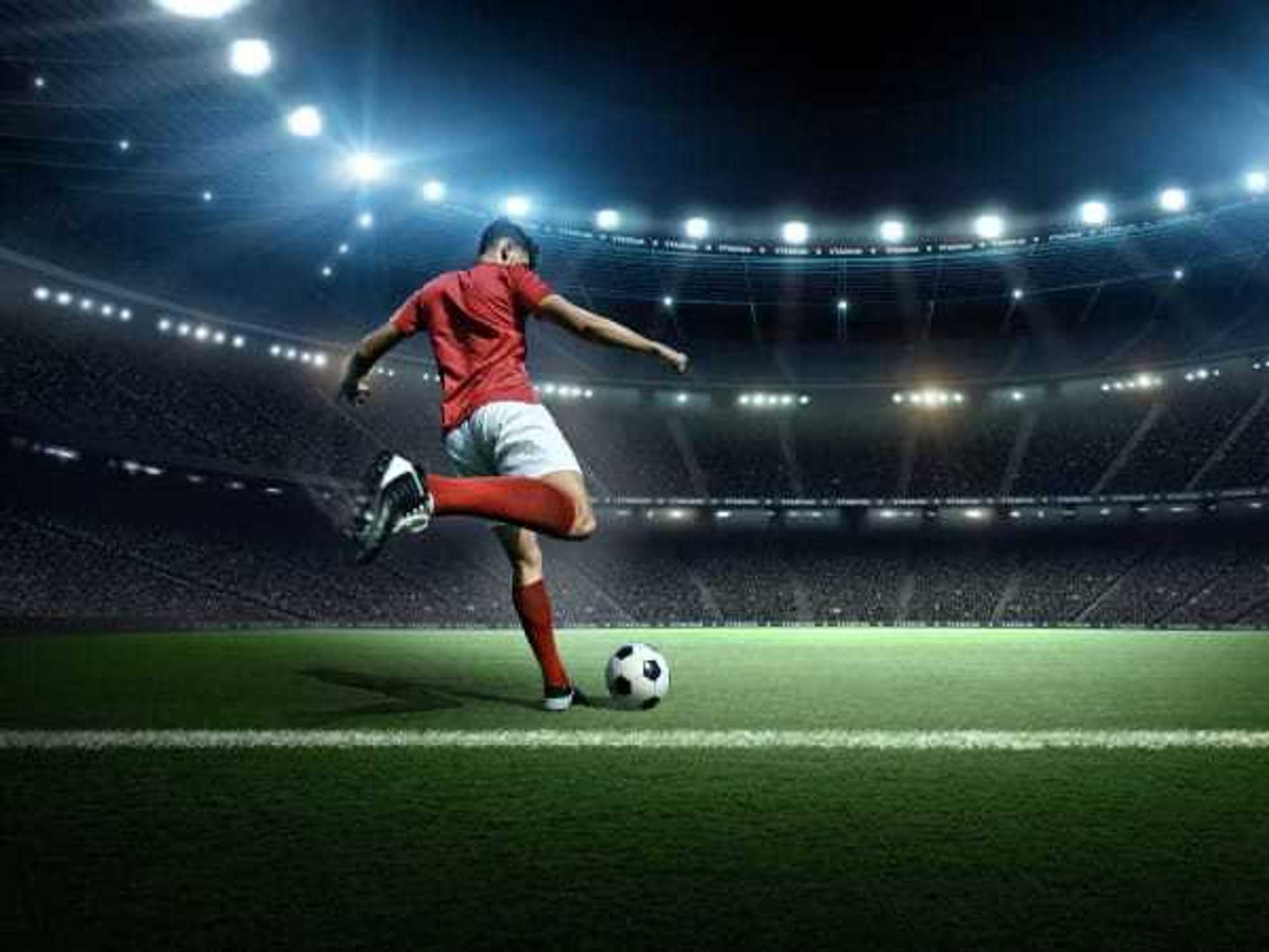 Soccer player is kicking a ball in the stadium.