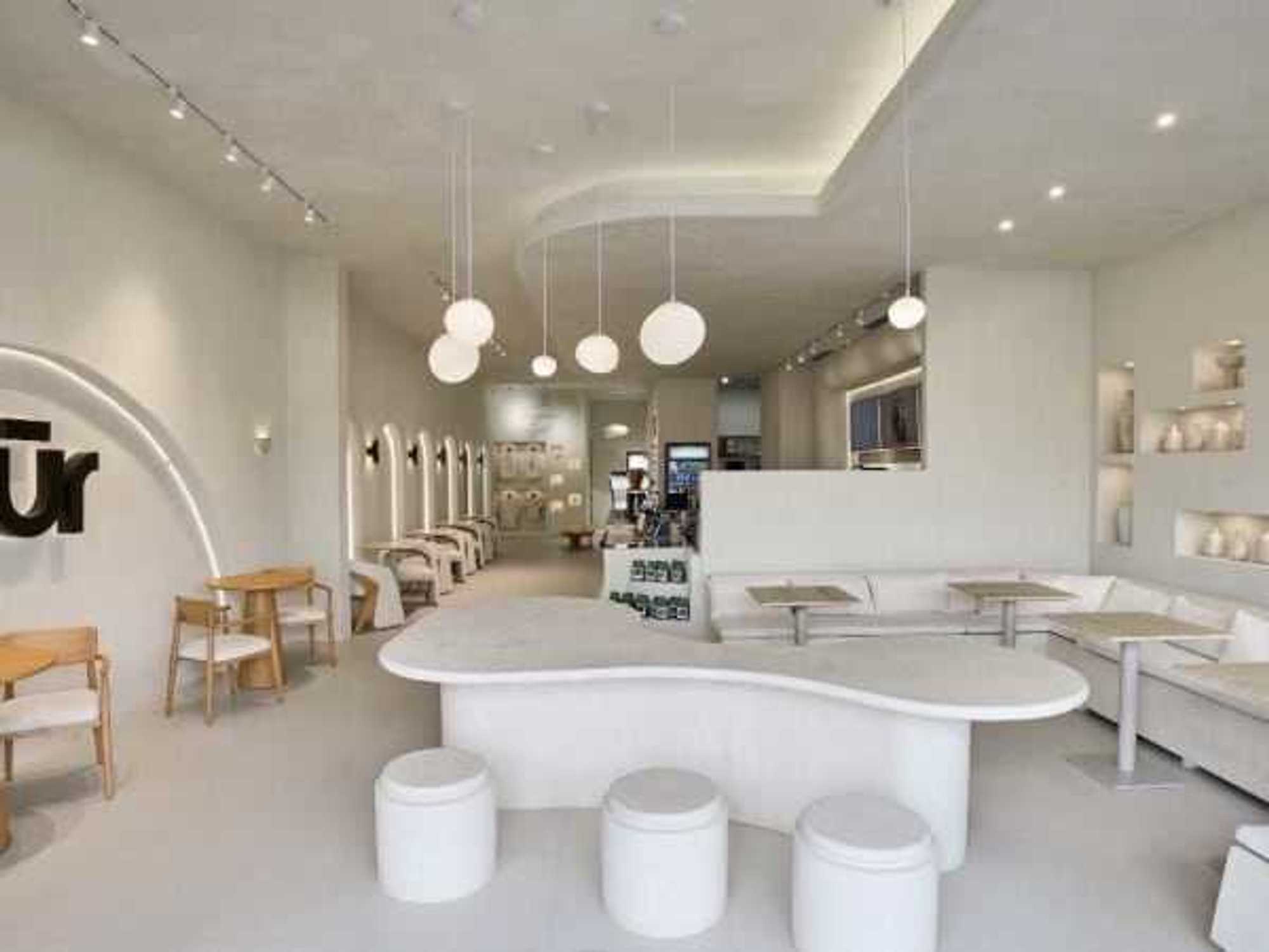 The interior of Nūr in Carrollton showcases a minimalist design with soft neutral tones, natural light, and comfortable seating.