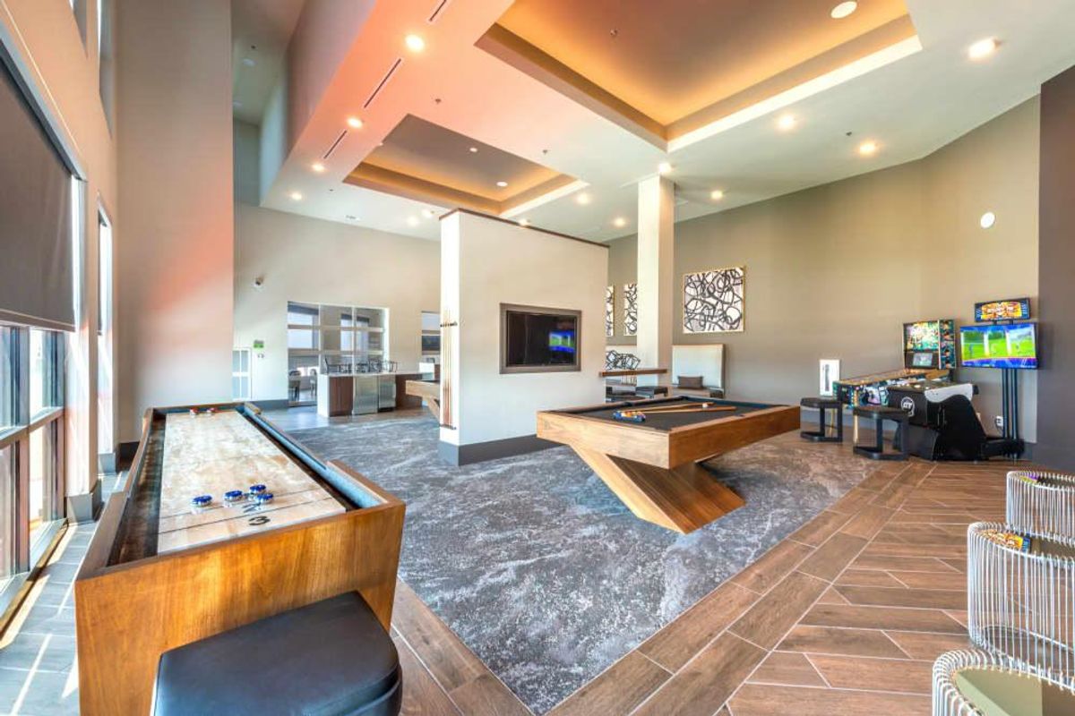 A bright and open game room has billiards, shuffleboard, Golden Tee